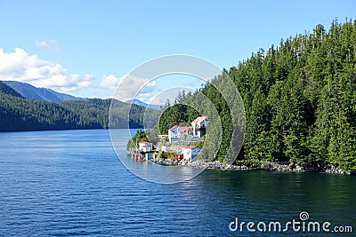 A view of a beautiful lighthouse in a remote location surrounded by forest and ocean along the inside passage ferry route. Stock Photo