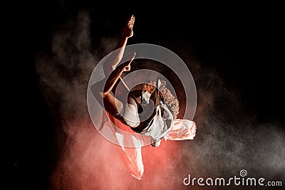 View of woman perfectly jumps and performs trick upside down in the air at dark Stock Photo