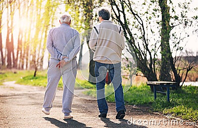 View from behind of an adult son walking with his senior father Stock Photo