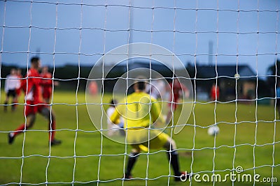 View from behind a footbal goal where the players are out of focus Stock Photo