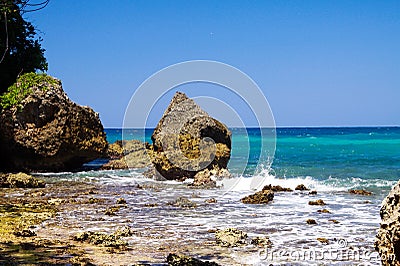 View beyond sharp rocks on turquoise rough sea with wave breakers and strong surf - Blue lagoon, Portland, Jamaica Stock Photo