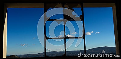 View of the blue sky and hills from the broken window of the abandoned cement factory Stock Photo