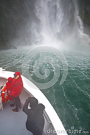 View from boat on Milford Sound, South Island, New Zealand. The front of the boat is taken very close to the waterfall. Editorial Stock Photo