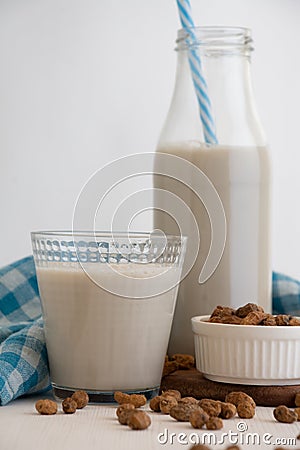 View of bottle with blue straw and glass with horchata and tiger nuts on white table Stock Photo