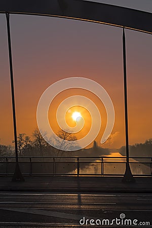 View through a bridge bow to a sunrise over a channel in Berlin on a misty morning with fairytale sunlight Stock Photo