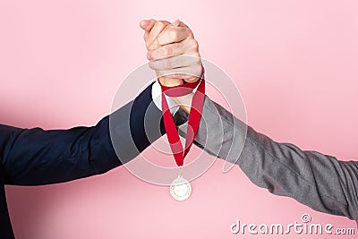 View of businessman and businesswoman holding hands and golden medal on pink, gender equality concept Stock Photo