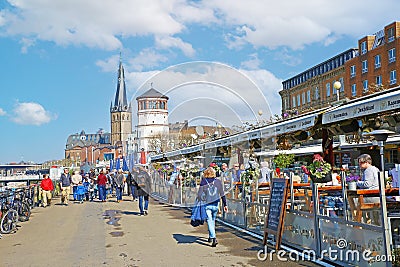 View on busy rhine river promenade with people sitting outside restaurant on sunny spring day Editorial Stock Photo
