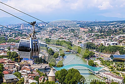 View of cable car above Tbilisi Georgia with view of Mtkvari - Kura River and Peace Bridge and city with mountains in the distance Editorial Stock Photo
