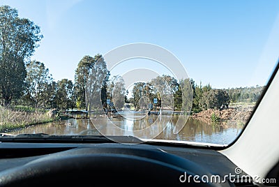 View from car of floodwater blocking the road rushing over a flooded bridge Stock Photo