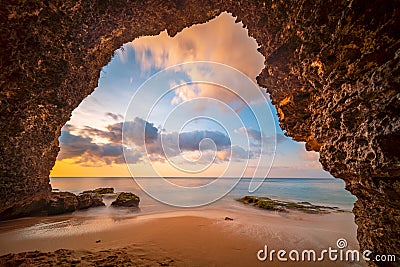 View from the cave a sandy beach along the ocean at sunset Stock Photo