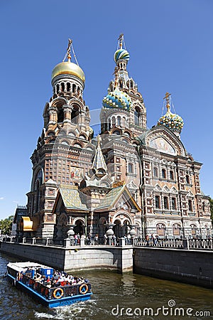 View of the Church of the Savior on Spilled Blood, Griboyedov Canal and a tourist boat with tourists floating on it. Editorial Stock Photo