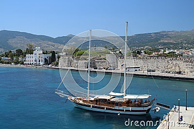 View on city wall of Kos City with sailing boat in front and mountains in the background Stock Photo