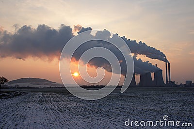 View of coal powerplant against sun and huge fumes Stock Photo