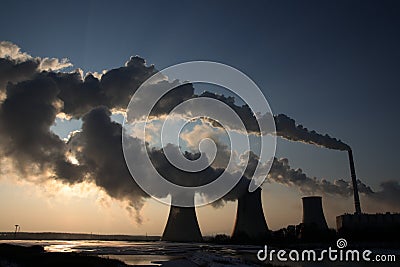 View of coal powerplant against sun and huge fumes Stock Photo