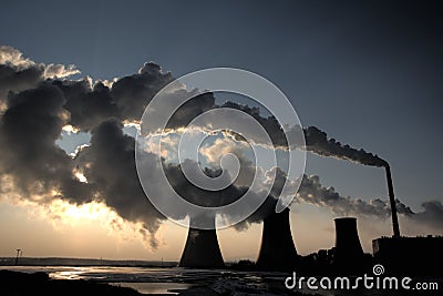 View of coal powerplant against sun and huge fumes Stock Photo