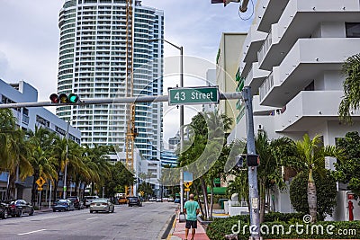 View of Collins Avenue with passing cars at the intersection of 43rd Street in Miami Beach against the backdrop of buildings. Editorial Stock Photo