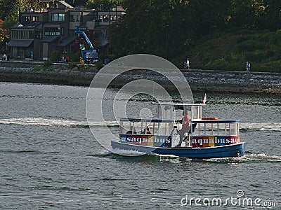 View of colorful little Aquabus boat, offering ferry connections in False Creek bay, Vancouver downtown with people passing by. Editorial Stock Photo