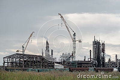 View of a complex of industrial buildings with smoking chimneys and construction cranes Stock Photo