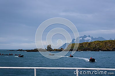 View of Coopers Bay landscape from cruise ship, fleet of inflatable rafts with drivers in red jackets getting ready to pick up tou Stock Photo