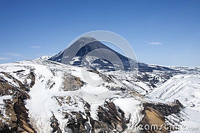 View of the correct cone of the Karymsky volcano in the spring after a snowfall Stock Photo