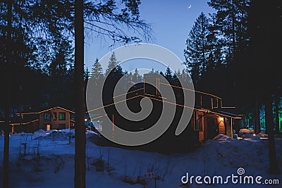 View of a cozy wooden scandinavian cabin cottage chalet house covered in snow near ski resort lodge in winter with the christmas Stock Photo