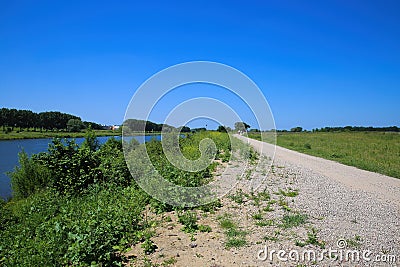 View on dirt cycling track along river Maas in typical rural dutch landscape in summer, near Venlo, Netherlands Stock Photo