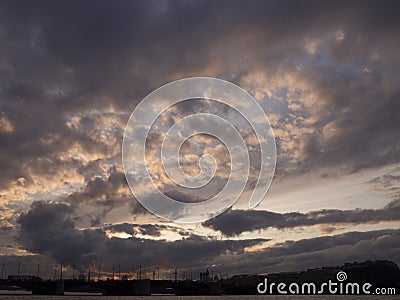 View of the dramatic sky above the sity at sunset with dark blue clouds and pink flashes Stock Photo