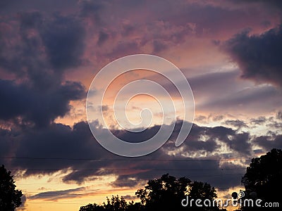 View of the dramatic sky above the sity at sunset with dark blue clouds Stock Photo