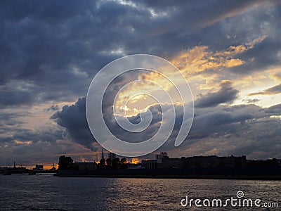 View of the dramatic sky above the sity at sunset with dark blue clouds and yellow flashes Stock Photo