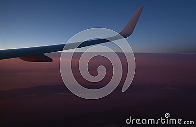 View of the earth from an airplane window from a height of 10,000 meters above the clouds illuminated Stock Photo