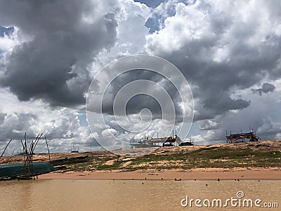 View of earthy brown lakes in Cambodia and abandoned pavilions when clouds cover the sun Stock Photo