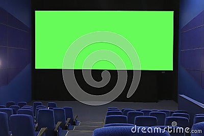 View of the empty cinema hall and a large green screen from the top rows. Cinema with rows of blue chairs Stock Photo