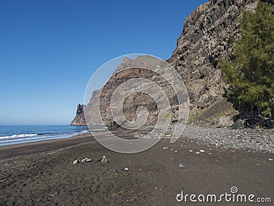 View of empty sand beach Playa de Guigui with rocky cliffs in west part of the Gran Canaria island, accessible only on Stock Photo