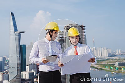 View of a Engineer and worker watching blueprint on construction site Stock Photo