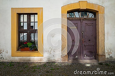 A view of the entrance to the townhouse. A large ornate wooden door and on the left a large sized window. Stock Photo