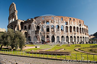 View of the exterior of the Colosseum in Rome with green meadow and ancient road in front on a spring day Editorial Stock Photo