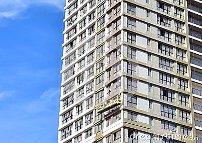 View of the facade of a new multi-storey building under construction. Suspended cradle on the facade of the skyscraper. Mobile Stock Photo