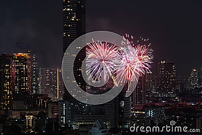 View of fireworks fireworks sparks explosions in the sky among tall buildings skyscrapers night city Stock Photo