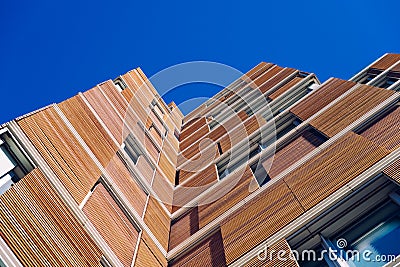 View from the floor of the facade of a modern building clad in ecological wood over clean blue sky, concept of sustainable Stock Photo