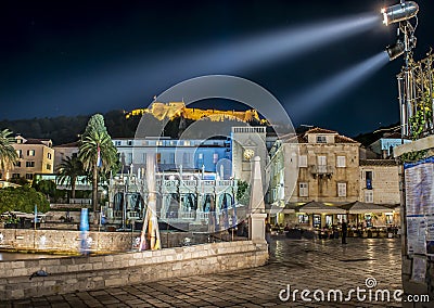 The fortress and the central square under the light beams of the island of Hvar at night Stock Photo