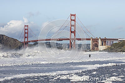 View of the Golden Gate Bridge with man fishing in huge waves Stock Photo