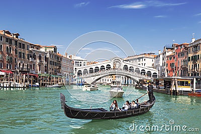 View of the Grand Canal, gondola with tourists and the Rialto Bridge. Venice Editorial Stock Photo