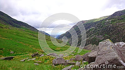 View across fields and valley towards base of mountain on PYG trail on Mount Snowdon in Snowdonia National Park, Wales, UK Stock Photo