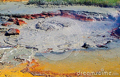 View on grey hot bubbling mud hole with red stones and yellow sulfuric ground Stock Photo