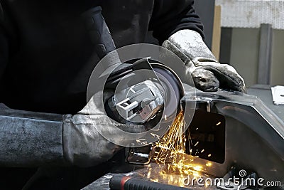 View of hands of worker grinding a piece of metal Stock Photo