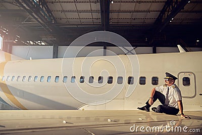 View of handsome captain of aircraft enjoying good weather in the open aviation hangar Stock Photo
