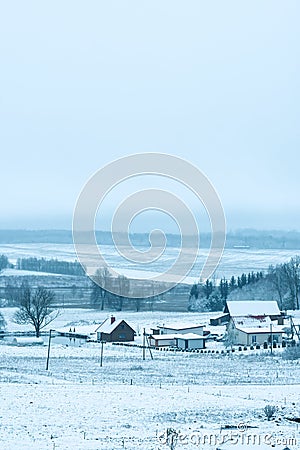 View from the hill to winter landscape with farmstead and forest, scenic winter view to valley Stock Photo