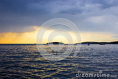 View of the horizon over the Adriatic Sea, with a boat sailing, during the sunset of a cloudy day while raining Stock Photo