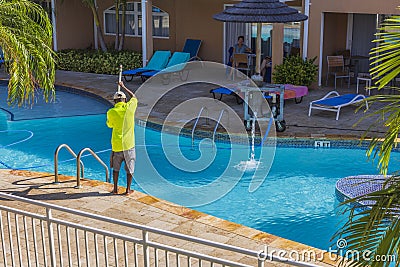 View of hotel's employee cleaning outdoor pool. Aruba. Editorial Stock Photo