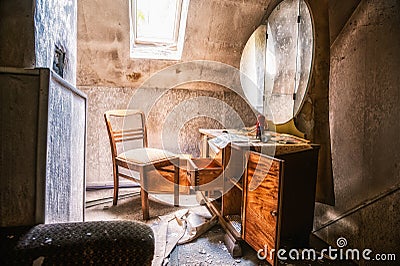 View inside an abandoned room with open wooden chest drawers and chair Stock Photo